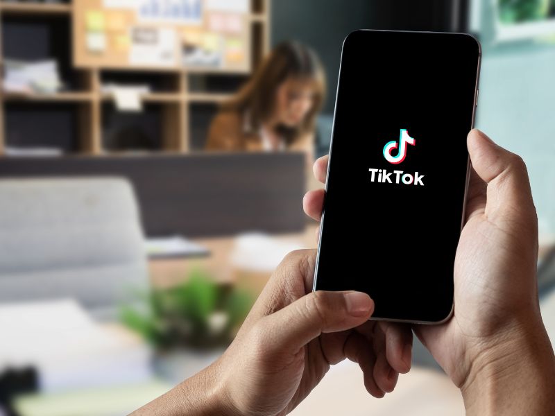 κρατώντας κινητό με tiktok logo